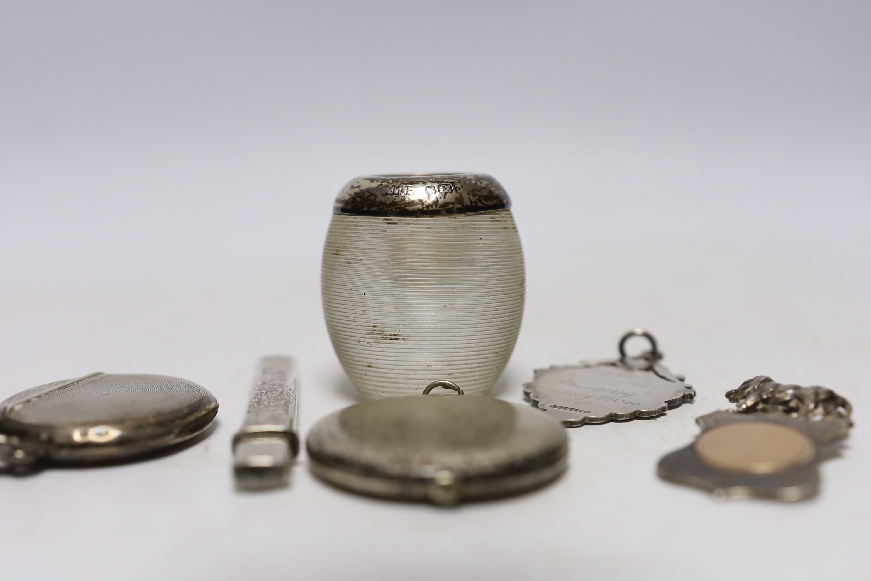 An early 20th century silver mounted ribbed glass match strike, 47mm and five other items including a silver vesta case, white metal locket, two medallions and a pencil.